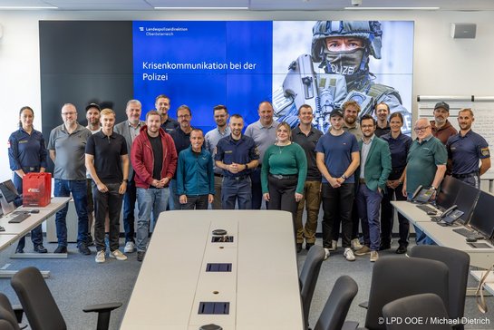 Krisenkommunikation bei der Polizei: Teilnehmende der LPD Oberösterreich posieren vor Großbildschirm